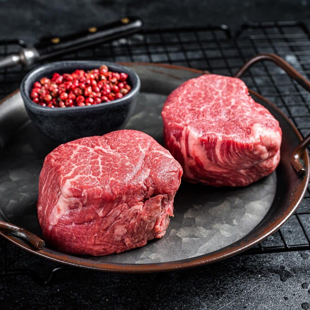 Two raw Christensen Ranch tenderloin steaks on a metal serving tray