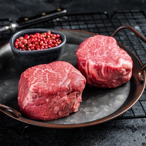 Two raw Christensen Ranch tenderloin steaks on a metal serving tray